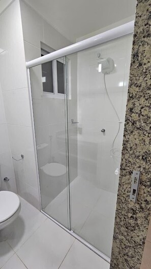 A modern bathroom with a glass-enclosed shower, a toilet, and a granite countertop. - Apartamento acesso ao diRoma Acqua Park (Caldas Novas)