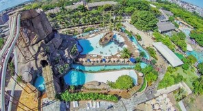 An aerial view of a resort with multiple swimming pools, a water slide, and lush greenery. - Apartamento acesso ao diRoma Acqua Park (Caldas Novas)