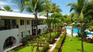 Un complexe hôtelier doté d’une piscine, de palmiers et d’un bâtiment blanc agrémenté de balcons.