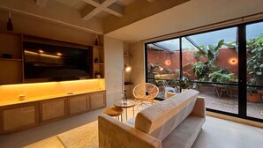 Una sala de estar moderna con sofá, televisor y comedor con sillas.