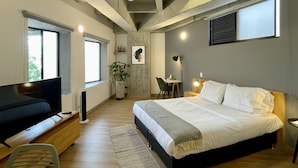 Un dormitorio moderno con una cama grande, un escritorio, una silla, un televisor y una planta.
