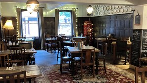 A restaurant interior with wooden tables and chairs, a patterned rug, and a vintage telephone booth. - 1777 The Albion (Wimborne)