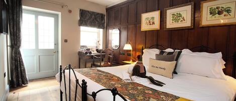 A hotel room with a bed, a desk, and a chair. There are framed pictures on the wall.