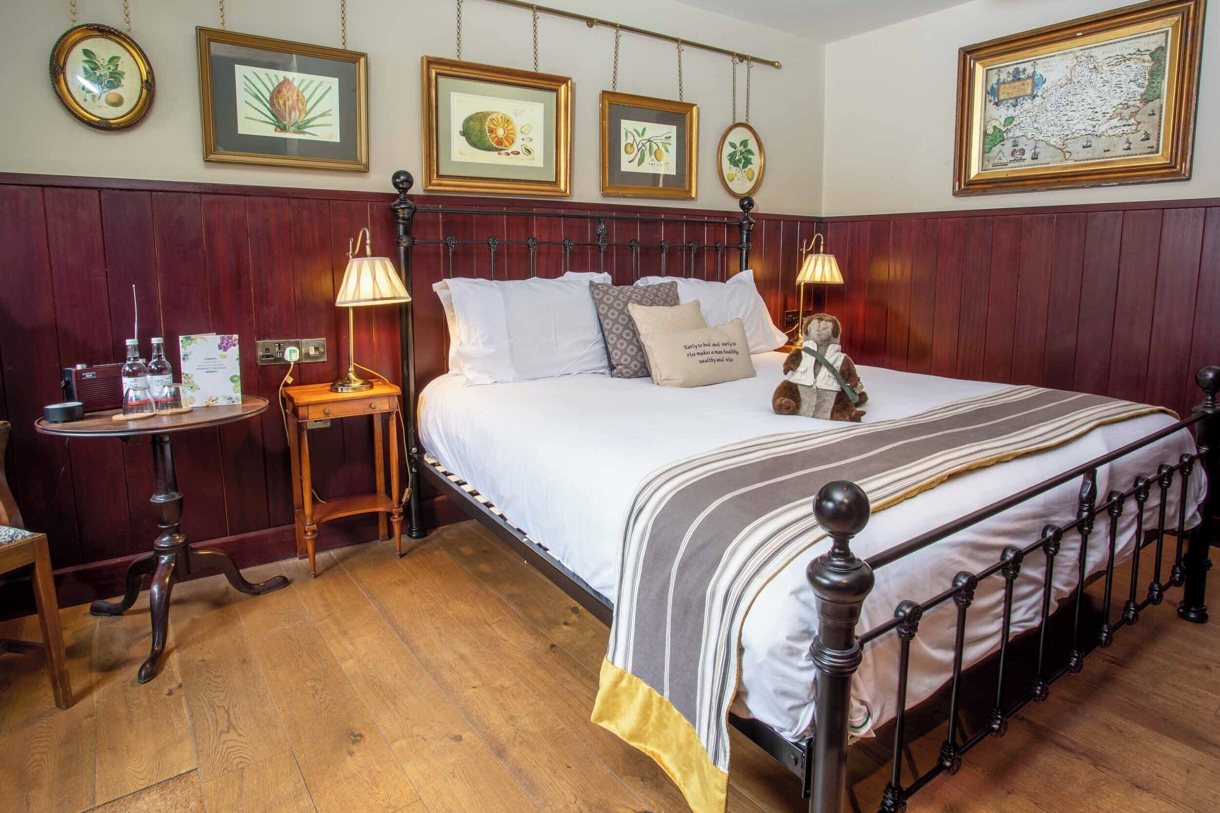 Une chambre à coucher bien aménagée, avec un lit en bois, des tables de chevet et des reproductions encadrées de motifs botaniques accrochées au mur.