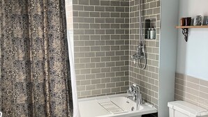 A bathroom with a bathtub, toilet, and shower. - 1777 The Albion (Wimborne)