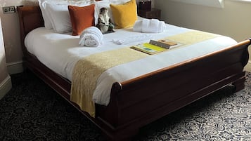 A neatly made bed with a patterned bedspread, pillows, and a folded towel.