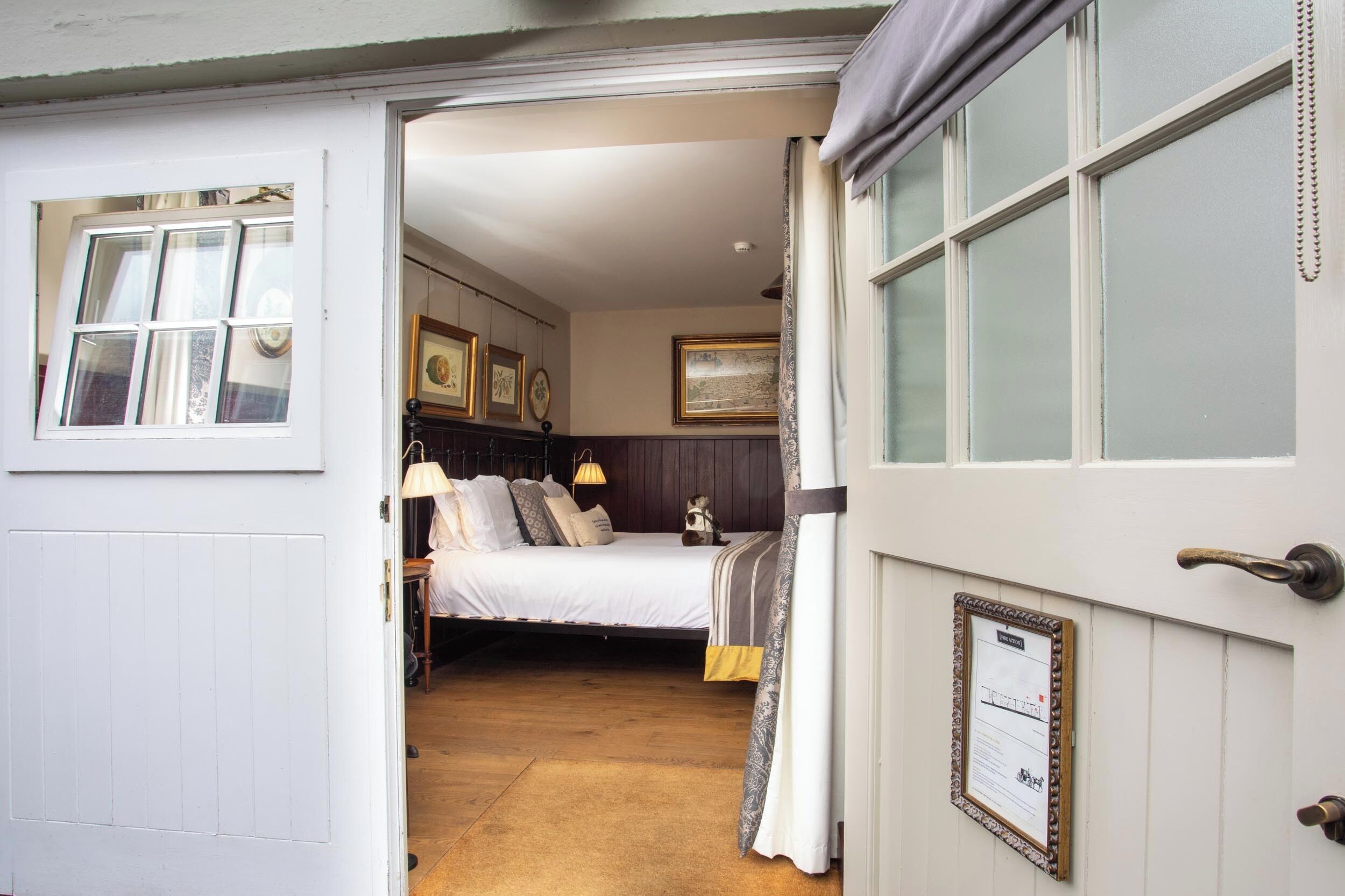 A bedroom with a bed, bedside lamps, a dresser, and a framed certificate on the wall.