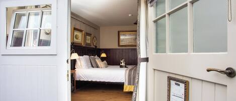 A bedroom with a bed, bedside lamps, a dresser, and a framed certificate on the wall.