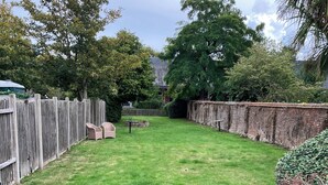 A backyard with a wooden fence, a brick wall, and a grassy lawn. - 1777 The Albion (Wimborne)