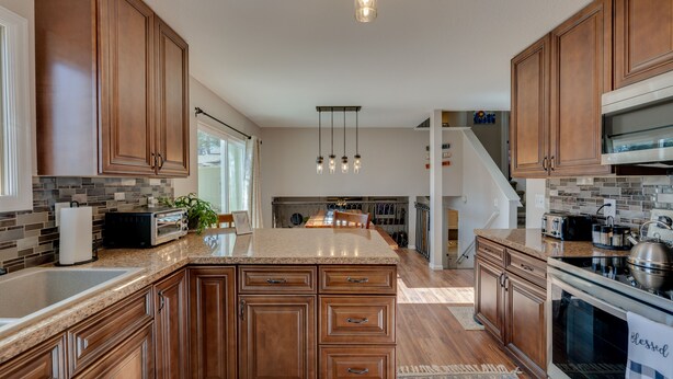 A modern kitchen with wooden cabinets, granite countertops, and stainless steel appliances. - Loveland Home w/ Private Hot Tub + Wood Fireplace! (Loveland)