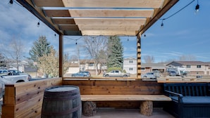 A covered outdoor seating area with wooden benches and a barrel. - Loveland Home w/ Private Hot Tub + Wood Fireplace! (Loveland)