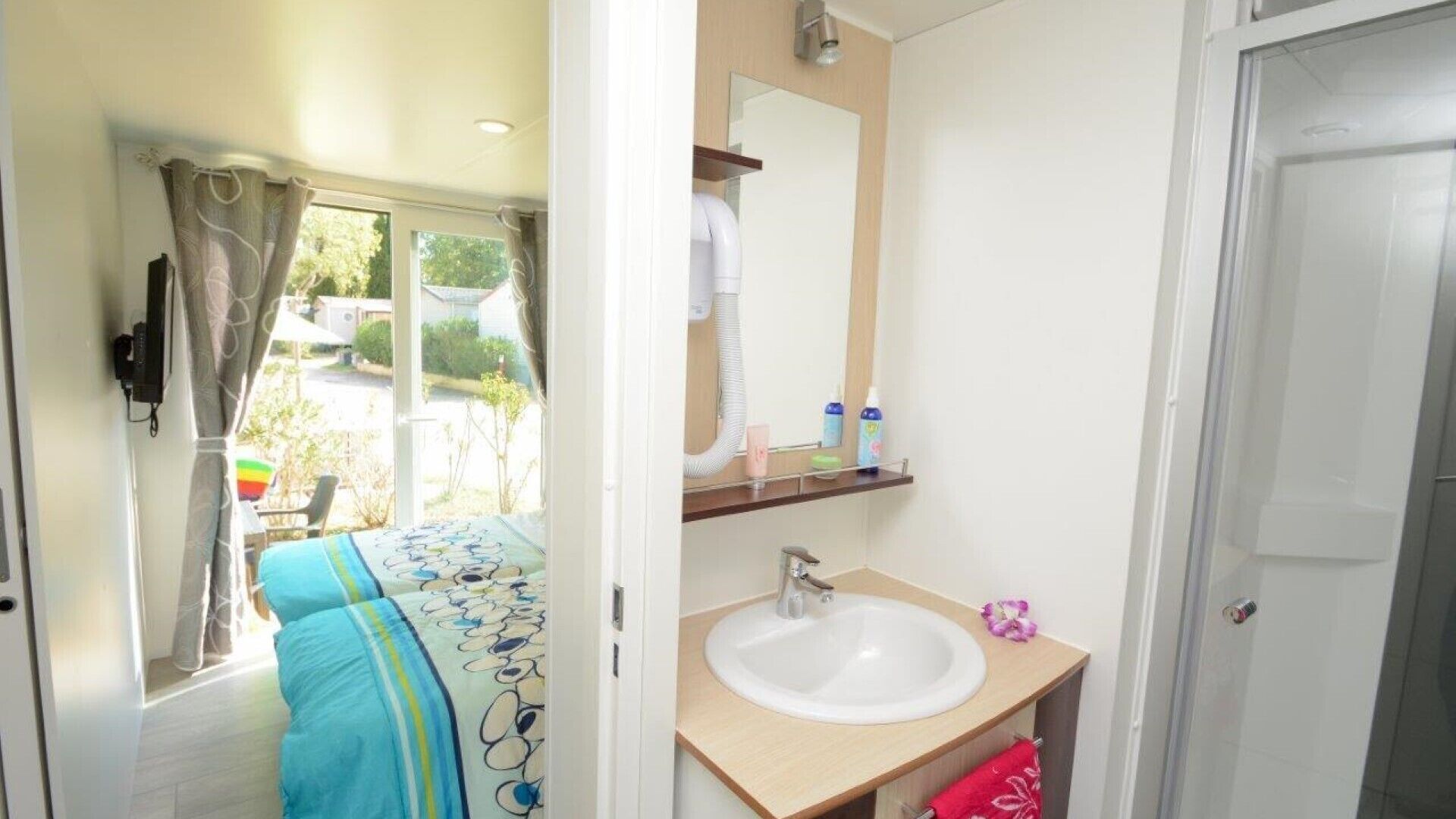 A compact bathroom with a sink, mirror, and a window with curtains.
