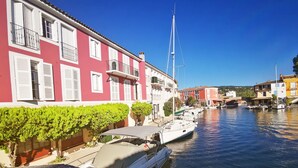 Un canal con barcos, un edificio rojo con contraventanas blancas y un velero amarrado cerca.
