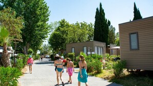 Un camino bordeado por casas móviles, rodeado de vegetación y árboles.