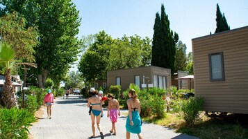 Un camino bordeado por casas móviles, rodeado de vegetación y árboles.