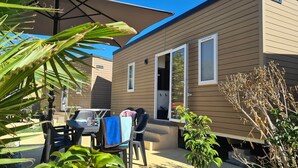 Una casa móvil con un patio, una mesa, sillas y un pequeño jardín.