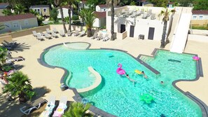 A swimming pool with lounge chairs and palm trees.