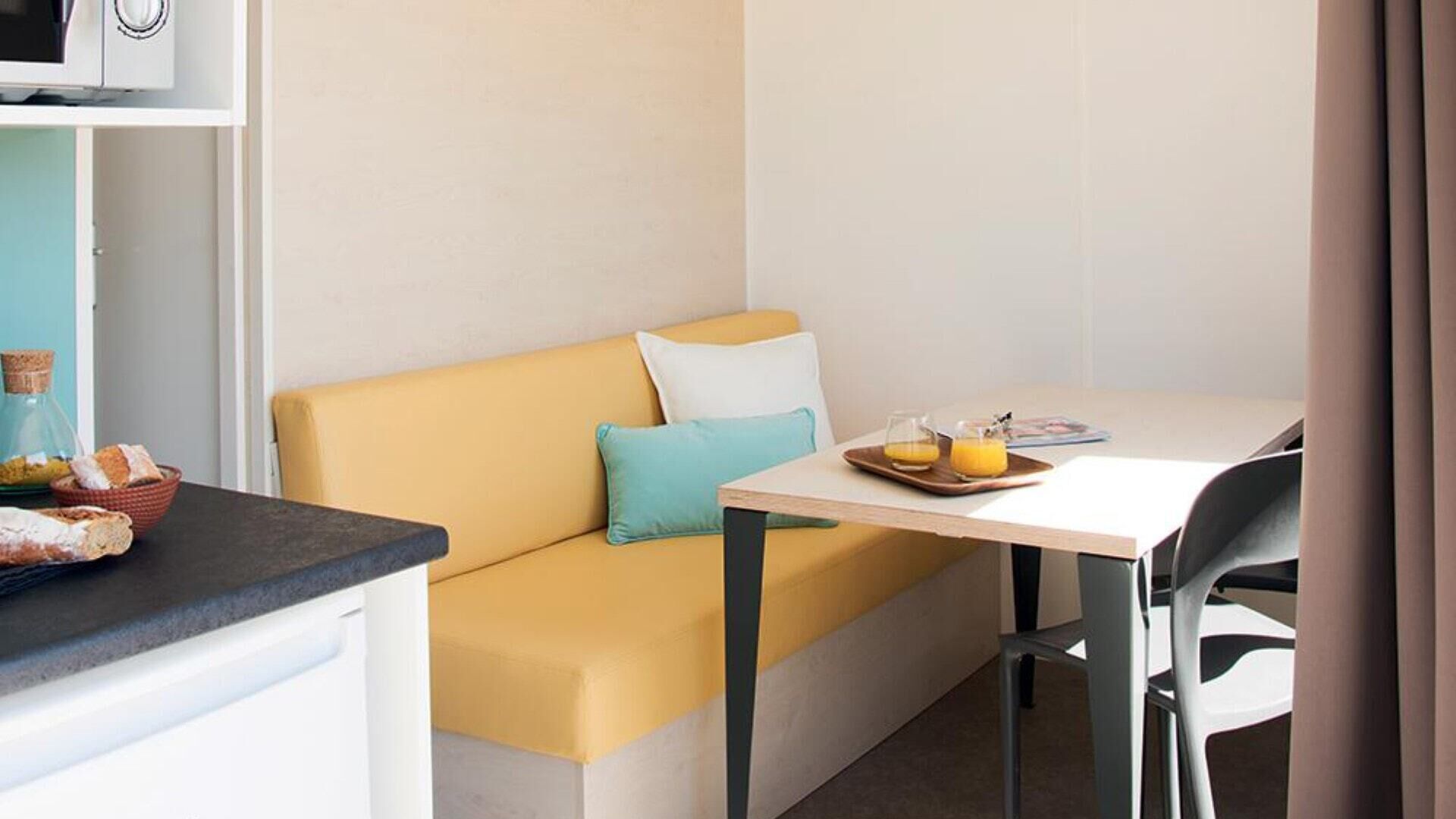 Une pièce de taille modeste comprenant un canapé, une petite table avec des articles pour le petit-déjeuner et un four à micro-ondes placé au-dessus du comptoir.
