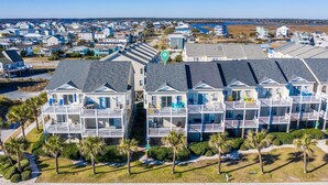 A beachfront condominium complex with multiple balconies, a pool, and a view of the ocean.