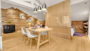 Ein Essbereich mit Holztisch und -stühlen, einer Backsteinwand und einer durchbrochenen Holzwand.