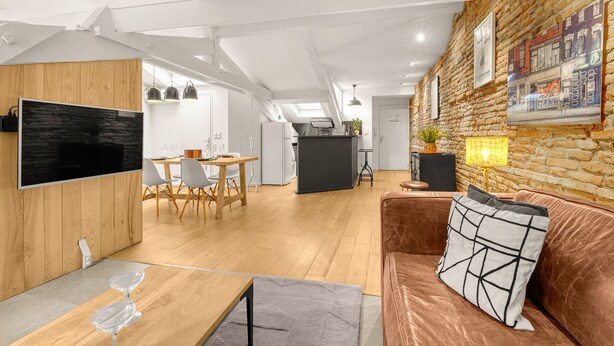 Ein modernes Wohnzimmer mit einem Holzesstisch, einer Ledersofa und einer Küchenzeile.