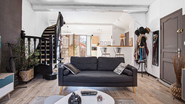 Ein Wohnzimmer mit einem grauen Sofa, einem Couchtisch und einer Treppe.