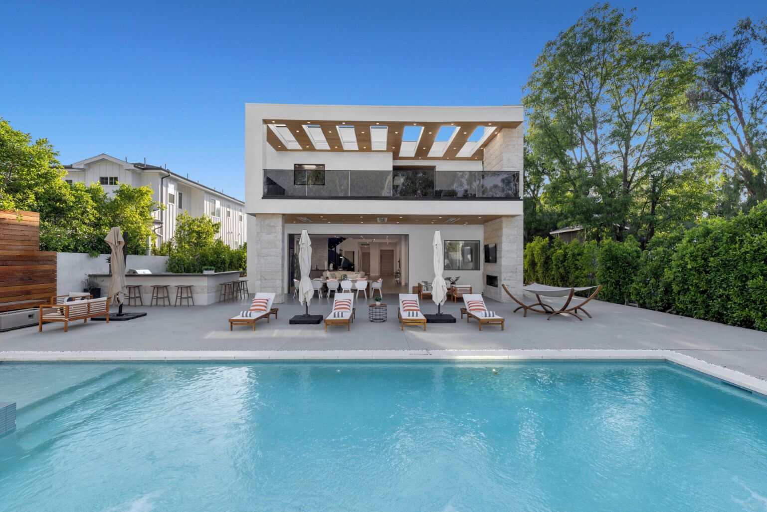 Een buitenzwembad, parasols bij het zwembad en ligstoelen