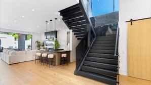 Une cuisine moderne dotée d’un îlot central, d’un escalier et d’un coin repas avec des tabourets de bar.