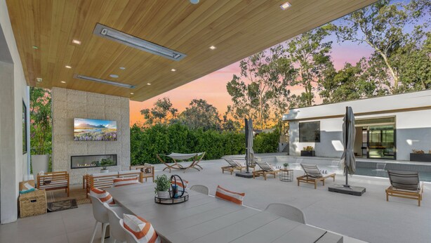 Un espace extérieur am énagé pour les repas, avec une piscine, des chaises longues et une vue sur le coucher de soleil.