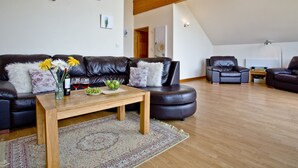 A modern living room with a leather sofa, a wooden coffee table, and a patterned rug.