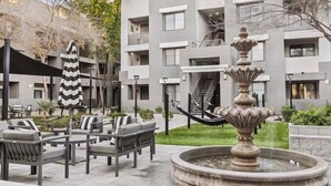 Un cortile con posti a sedere all'aperto, una fontana e un edificio con balconi e finestre.
