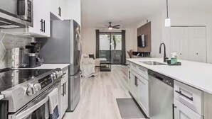 Una cucina moderna con elettrodomestici in acciaio inossidabile, un'area pranzo con divano e vista panoramica tramite una porta in vetro.