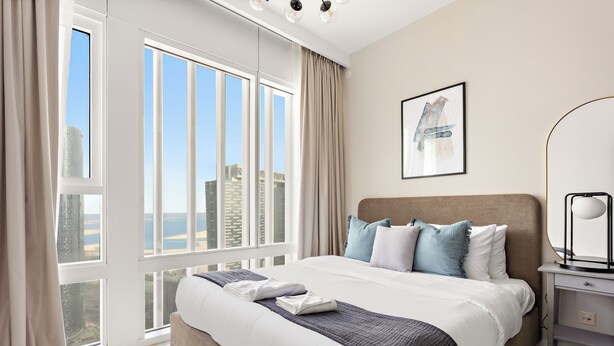 A modern hotel room with a large bed, a view of the city, and a minimalist decor.