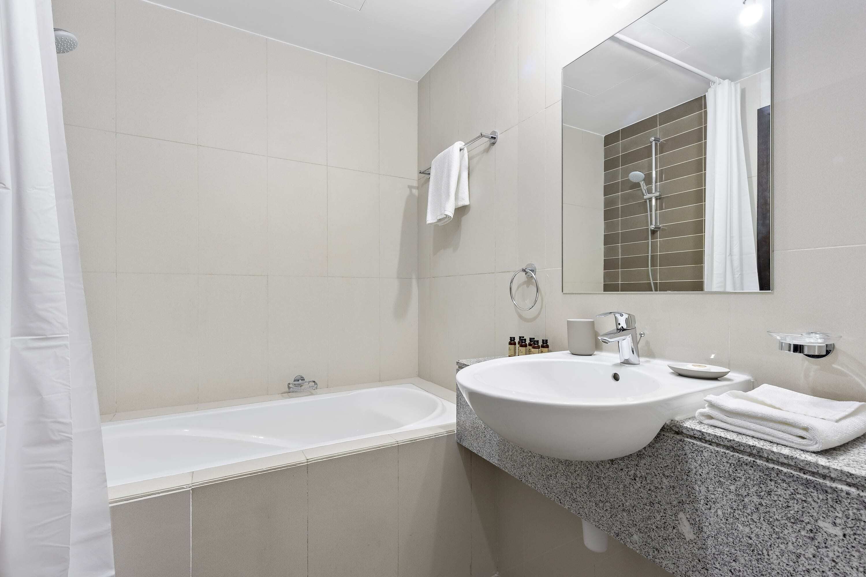 A modern bathroom with a bathtub, a sink, and a mirror.