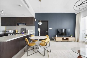 A modern kitchen with dark cabinets, a white countertop, and a dining area with a round table and yellow chairs.