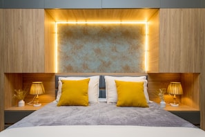 Un dormitorio moderno con una cama grande, dos lámparas de noche y un panel de pared original.