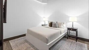 Ein modernes Schlafzimmer mit einem großen Bett, zwei Nachttischen mit Lampen und einem gemusterten Teppich.