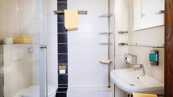 Ein modernes Badezimmer mit Duschkabine aus Glas, einem weißen Waschbecken und einer Toilette.