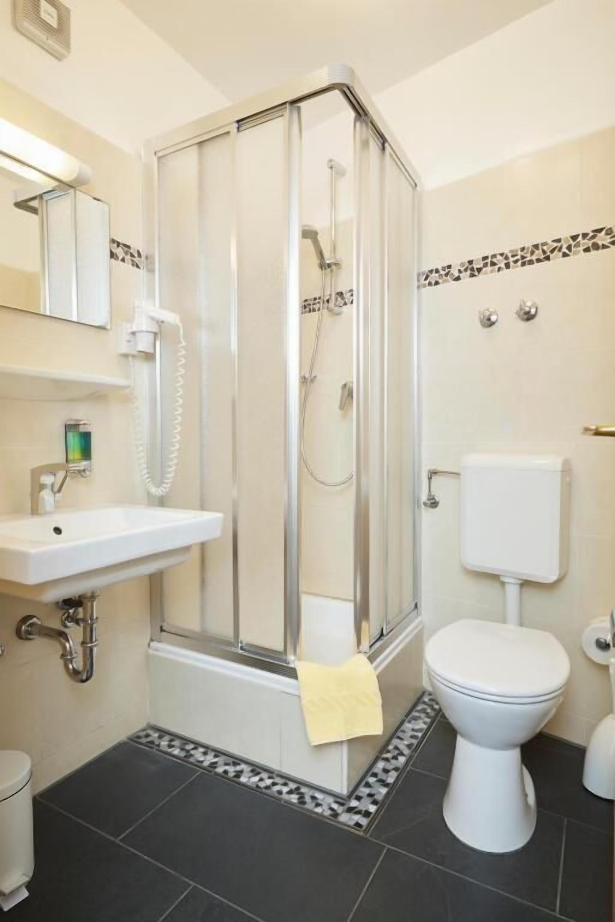 Un baño con cabina de ducha, lavamanos, inodoro y espejo.