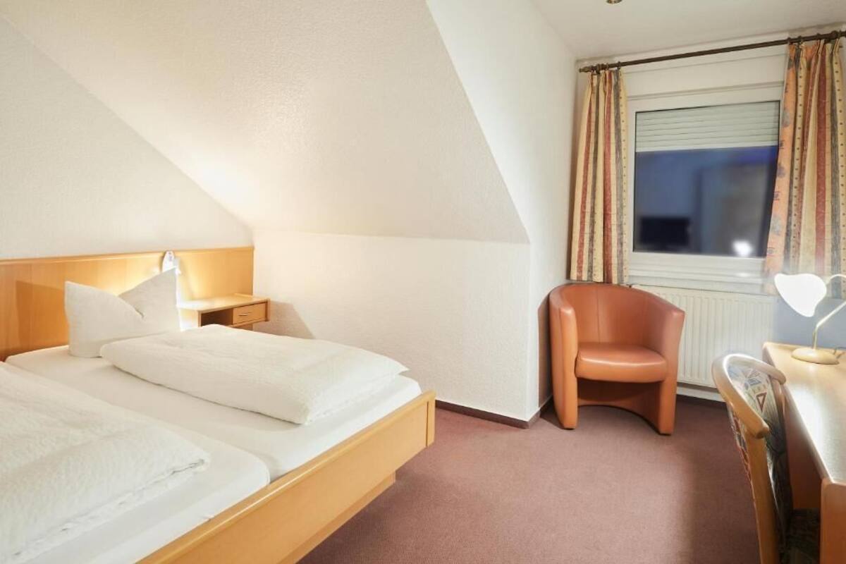 A hotel room with two beds, a desk, a chair, and a window with curtains.