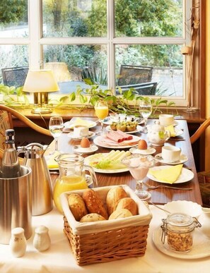 A breakfast table set with various dishes, a coffee pot, and a basket of bread. - Park Hotel Berlin (Bad Fallingbostel)