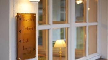 Ein Schild mit Pfeilen, die zu 'Reception', 'Restaurant', 'Cafe' und 'Terrasse am Teich' weisen.