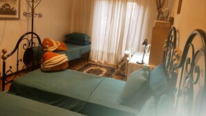 Un dormitorio con cama, escritorio, silla, espejo y ventana con cortinas.