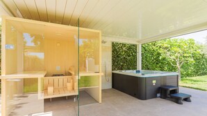 A modern outdoor hot tub area with a glass enclosure, a wooden bench, and a step stool. - Affittacamere Incanto nel Verde by Wonderful Italy (Polignano a Mare)