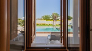 A view from a room with a sliding glass door to an outdoor area with a swimming pool, lounge chairs, and a tree. - Affittacamere Incanto nel Verde by Wonderful Italy (Polignano a Mare)