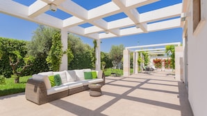 An outdoor patio with a white pergola, a wicker sofa with cushions, and a small round table. - Affittacamere Incanto nel Verde by Wonderful Italy (Polignano a Mare)