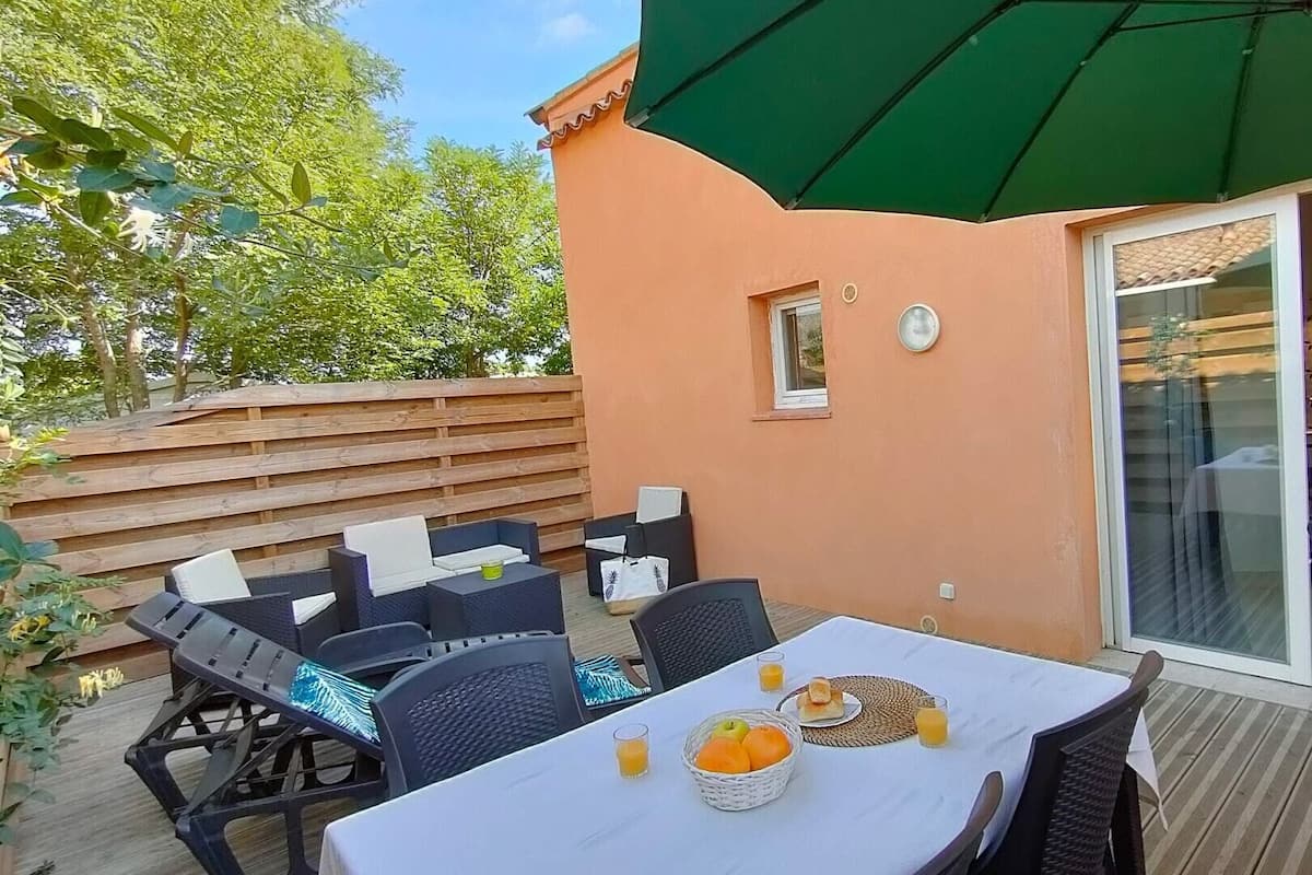 Eine Terrasse im Freien mit einem für das Frühstück gedeckten Tisch, umgeben von Stühlen und einem Sonnenschirm.