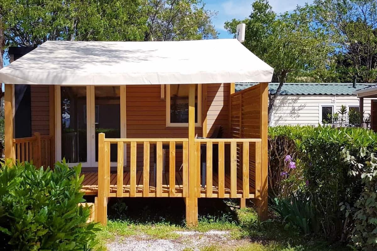 Eine Holzhütte mit überdachter Veranda und einer Treppe zum Eingang.