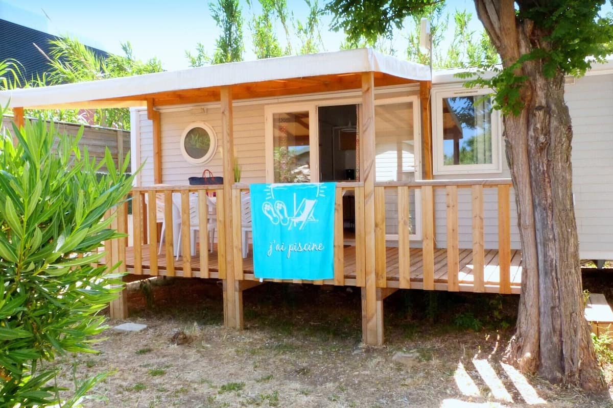 Eine Holzterrasse mit einem blauen Handtuch, umgeben von Bäumen und einem kleinen Garten.
