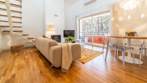 Una sala de estar moderna con sofá, televisor y un comedor con sillas y mesa.